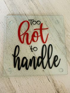 a glass sign that says too hot to handle on a white wooden background with black and red lettering