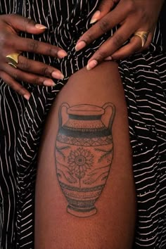 a woman's legs with tattoos on them and a vase tattoo on the leg