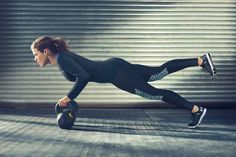 a woman is doing push ups with a kettle