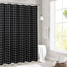 a black and white shower curtain in a bathroom next to a window with a brick wall