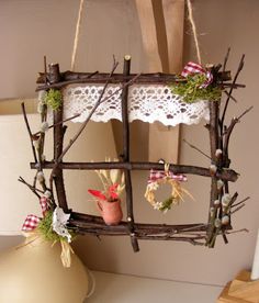 a wooden frame hanging from the ceiling with branches and flowers on it next to a vase