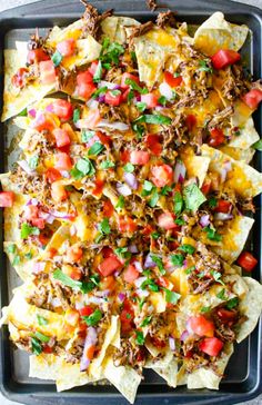 nachos with meat, tomatoes and onions on a tray