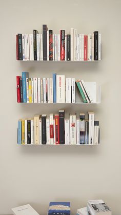 two white bookshelves filled with different colored books on top of eachother