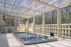 an indoor hot tub in the middle of a patio with glass walls and white railings