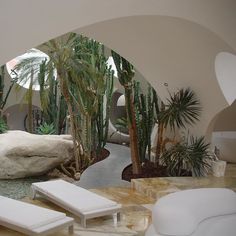 an indoor area with white furniture and palm trees in the background, including two chaise lounges