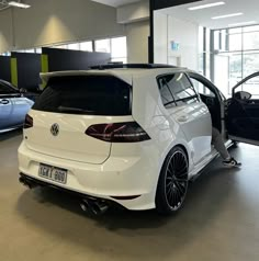 the back end of a white car in a showroom