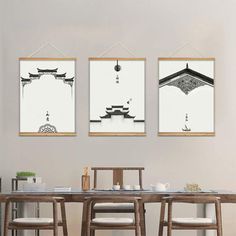 three framed pictures hang on the wall above a dining room table