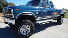 a blue pick up truck parked on the side of a road next to a field