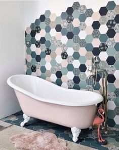 a bath tub sitting on top of a tiled floor next to a pink flamingo