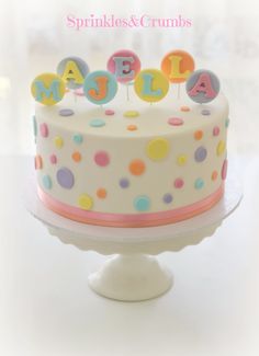 a birthday cake decorated with polka dots and the words spelled out in small colorful letters