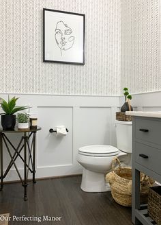 a white toilet sitting in a bathroom next to a wooden table with a potted plant on it