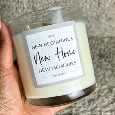 someone holding a candle in their hand with the words new beginnings, new home on it