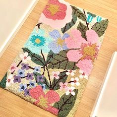 a laptop computer sitting on top of a wooden floor next to a flowered rug