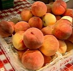 a pile of peaches sitting on top of a red and white checkered table cloth