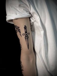 a person with a tattoo on their arm holding a knife and dagger in the other hand