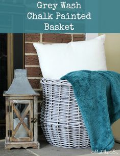 grey wash chalk painted basket sitting next to a white pillow and lantern with text overlay that reads gray wash chalk painted basket