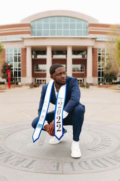 a man kneeling down in front of a building with a scarf around his neck and numbers on it