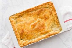 a square white dish filled with food sitting on top of a red and white towel