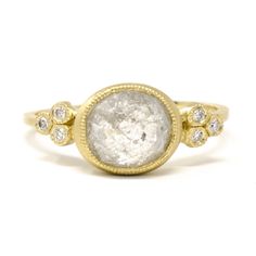 a gold ring with a white diamond in the center and two diamonds on each side