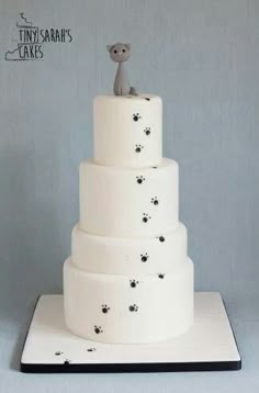 a three tiered cake with a cat figurine on top and paw prints