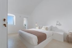 a bedroom with white walls and beige bedding