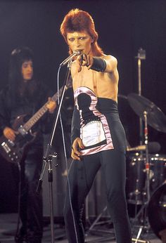 an image of a man that is on stage with his shirt off and holding a microphone