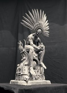 a statue of a man sitting on top of a table next to a black and white photo