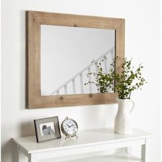 a white table topped with a mirror and a vase filled with flowers