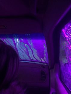 the inside of a car with purple lights and water on the windshield, as well as an aquarium in the passenger seat