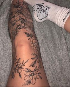 a person laying on a bed with their legs covered by socks and flowers tattooing them