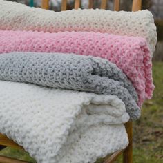 three crocheted blankets sitting on top of a wooden chair