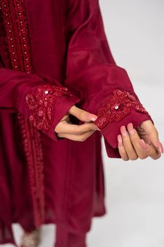 A maroon cotton raw silk suit with matching maroon sequins with cut work on the sleeves and paired with a matching colored net organza dupatta. 3-Piece Suit Ready to wear Red Designer Lawn Suit With Sheer Dupatta, Party Kurta With Embroidered Long Sleeves, Elegant Lawn Suit With Embroidered Long Sleeves, Elegant Lawn Suit With Long Embroidered Sleeves, Red Organza Anarkali Set With Dabka Detail, Eid Cotton Silk Set With Embroidered Sleeves, Red Organza Anarkali Set With Dabka, Red Cotton Silk Party Sets, Fitted Sets With Embroidered Sleeves For Eid