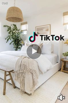 a white bed sitting in a bedroom next to a wooden table and plant on top of it