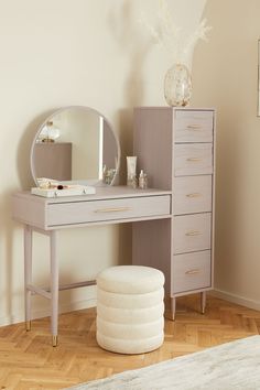 a vanity table with a mirror, stool and vase on the floor next to it