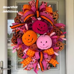 a pink and orange halloween wreath with pumpkins, jack - o'- lantern faces