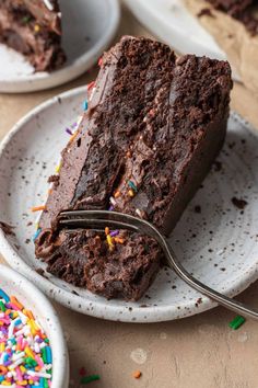 a piece of chocolate cake with sprinkles and a fork on a plate