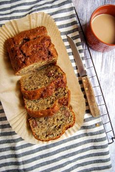 slices of banana bread sitting on top of a paper plate next to a cup of coffee