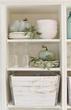 the shelves in this kitchen are filled with dishes and glassware, including pumpkins