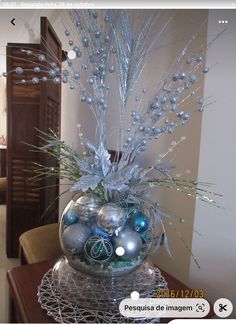 a glass vase filled with ornaments on top of a metal stand in a living room