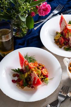 two white plates topped with food on top of a table next to silverware and flowers