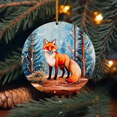 a christmas ornament with a red fox on it hanging from a pine tree