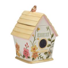 a ceramic birdhouse with flowers painted on it's side and a bird perched on top