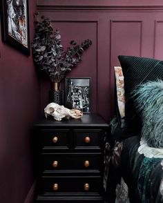 a bedroom with purple walls and a black dresser in the corner next to a bed