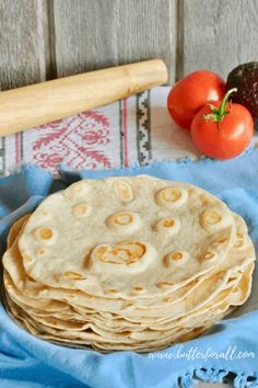 a stack of tortillas sitting on top of a blue towel next to tomatoes