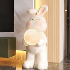 a white rabbit holding a round object in its hands while standing next to a wall