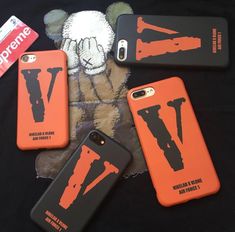 four phone cases are laying on top of a black cloth with an orange and black design