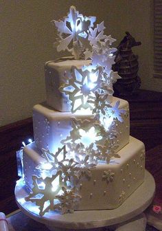 a three tiered white cake with snowflakes on it