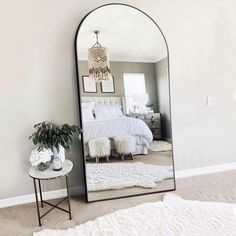 a large mirror sitting on top of a floor next to a white rug and table