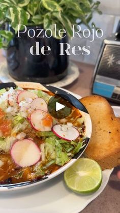 a bowl of food on a plate with bread and limes in front of it