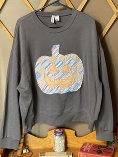 This is a repurposed sweatshirt with vintage quilt pumpkin sewn on the front of it.   Sweatshirt  brand Divided H&M  size x large it's a pretty medium gray color. please see pictures with ruler for measurements. Sweatshirt measures approx 27 inches from armpit to armpit.  And, approx 21 inches from the crew neck to the bottom. Please note that the quilt may have Thinning fabric, exposed padding, mild discoloration. The sweatshirt is freshly washed in all free and clear. Please ask questions and Gray Fall Patchwork Sweatshirt, Gray Patchwork Crew Neck Sweatshirt, Gray Crew Neck Sweatshirt With Patchwork, Repurposed Sweatshirt, Pumpkin Applique, Divided H&m, Quilted Sweatshirt, Pumpkin Sweatshirt, Diy Sweatshirt